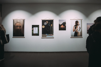 Zu sehen sind sechs Fotografien an einer weißen Wand links und rechts sind Besucher der Ausstellung